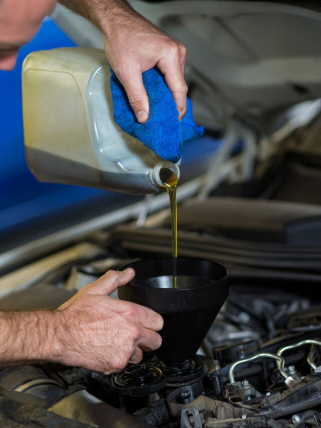 Mechanic pouring oil into car engine